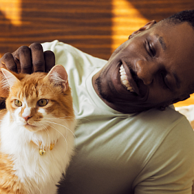 A man smiling and petting his cat